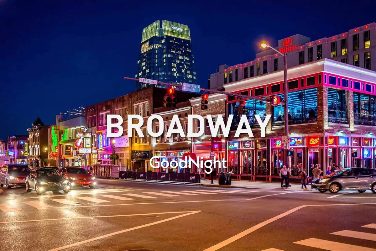A vibrant, neon-lit street scene filled with energy, featuring a busy road lined with dining spots and music venues. The high-rise building hints at the urban nightlife, while people enjoy live music and the excitement of Nashville's downtown after dark.