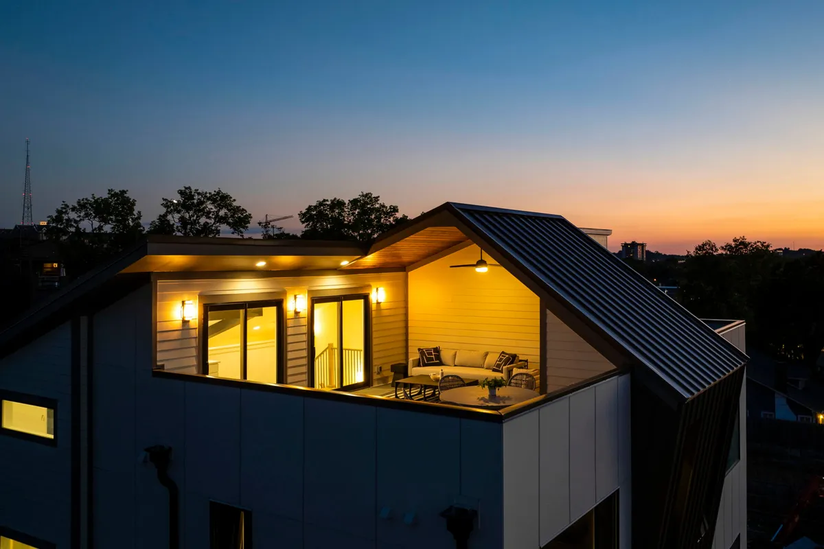 This exterior shot showcases a cozy outdoor seating area bathed in warm lighting, with large windows suggesting the spaciousness and inviting atmosphere inside. The setting is tranquil and perfect for relaxing or entertaining guests, with sunset views creating a sense of peace and exclusivity.