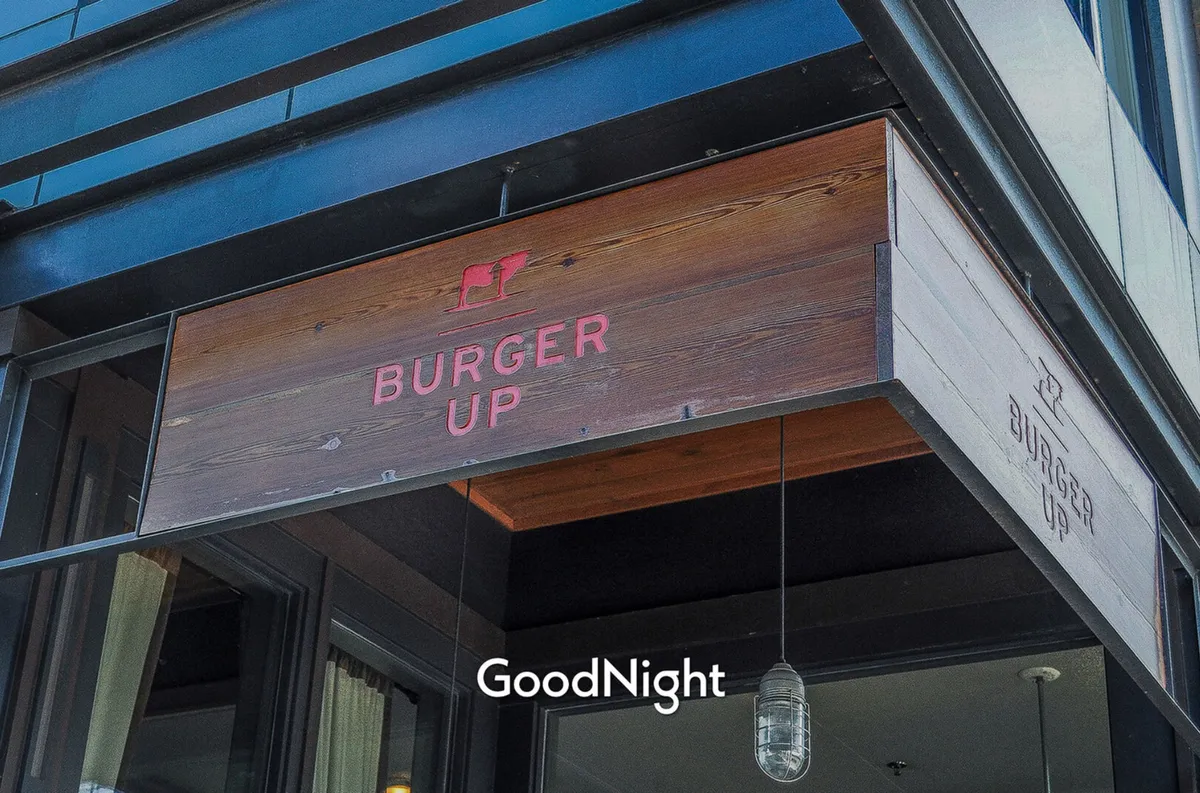 A close-up of the 'BURGER UP' signage with a glowing hanging light, capturing the casual and welcoming essence of a local eatery. The image focuses on the entryway, inviting visitors to step in and enjoy gourmet burgers in a relaxed setting.