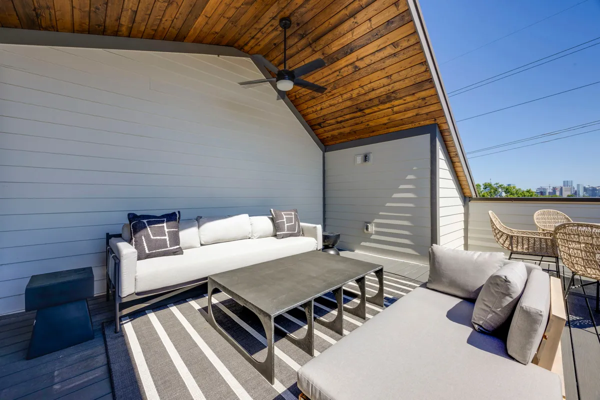 An inviting exterior terrace with modern seating, a striped rug, a wooden ceiling, and an outdoor dining set. The space is designed for both relaxation and social connection, offering scenic views that reflect the luxury and comfort of the GoodNight Luxe experience.