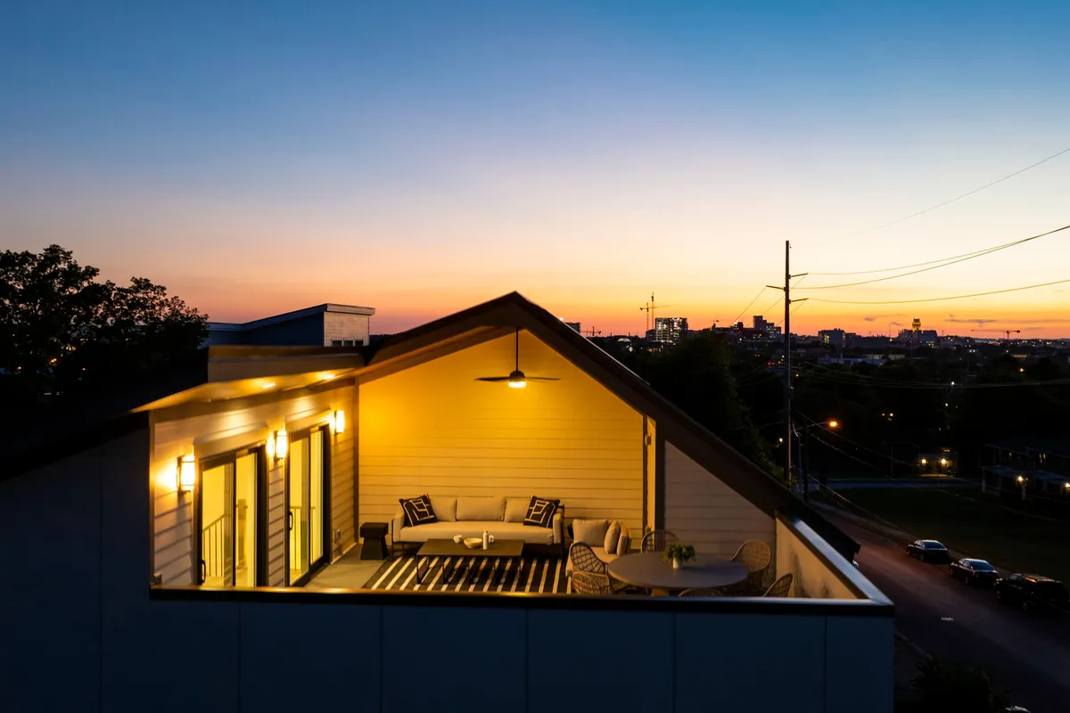 A tranquil exterior seating area with a table set amidst plants and a breathtaking city skyline in the background. The ambiance is cozy and intimate, ideal for evening gatherings, stargazing, and enjoying the vibrant city from a peaceful retreat.
